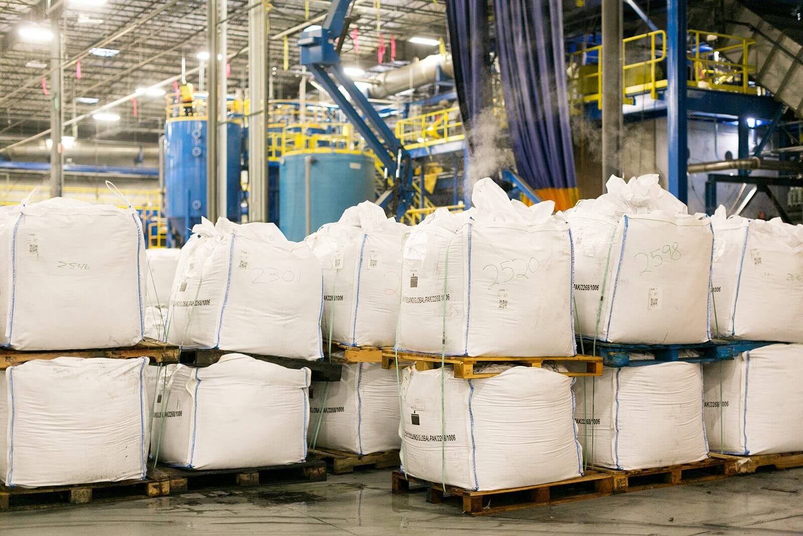 Bulk bags of black mass staged on pallets inside a processing facility